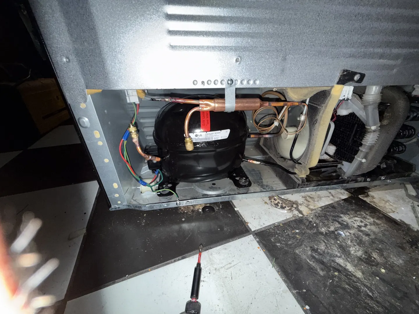 A refrigerator compressor compartment opened for sealed-system work