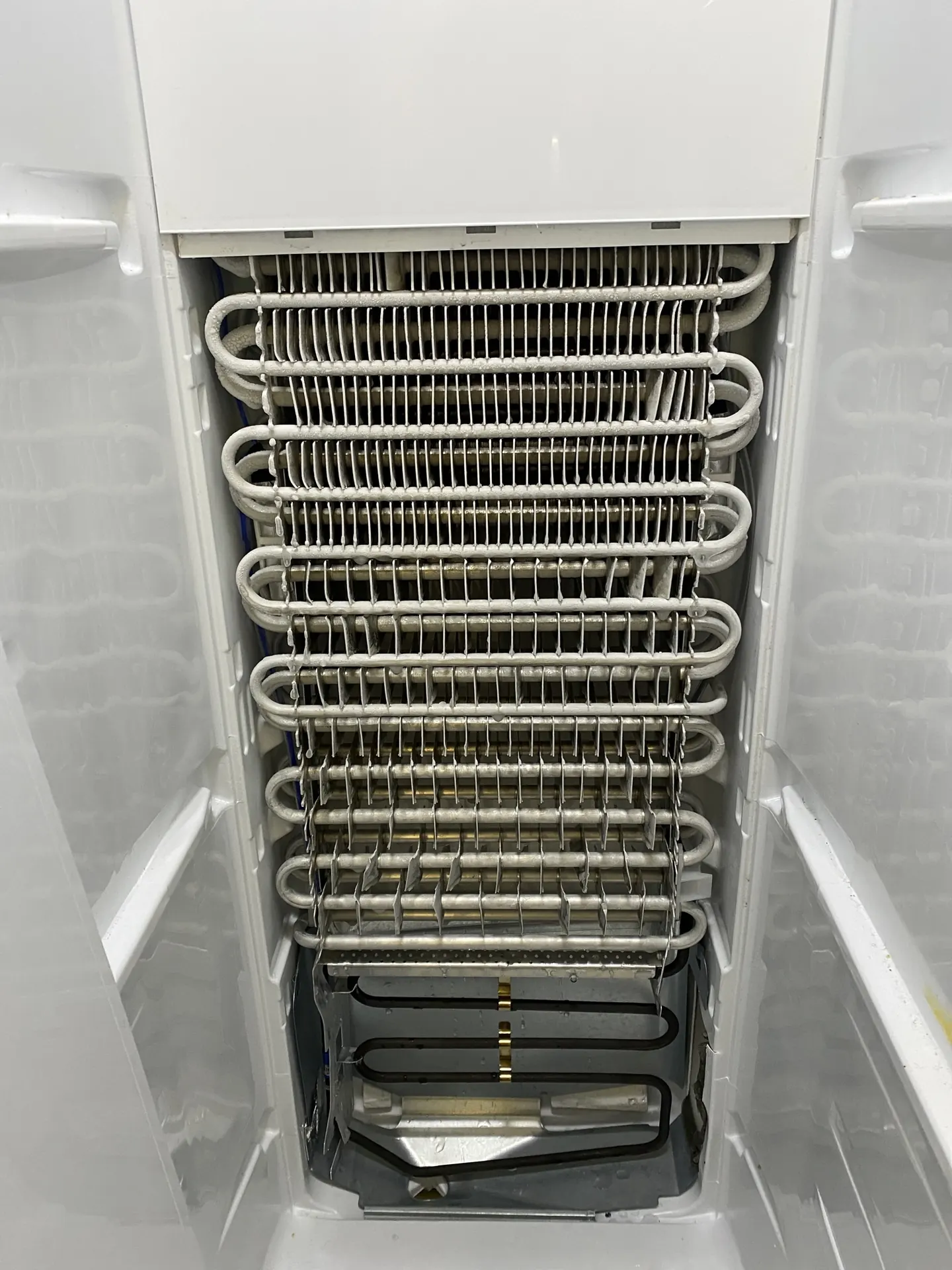The evaporator coil inside a refrigerator freezer, exposed during a repair