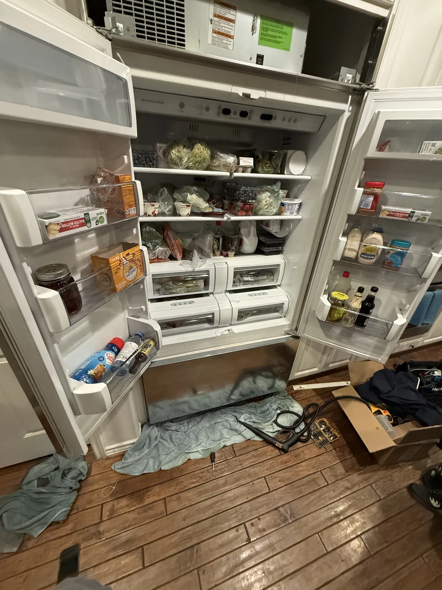 An open refrigerator in a kitchen after the repair