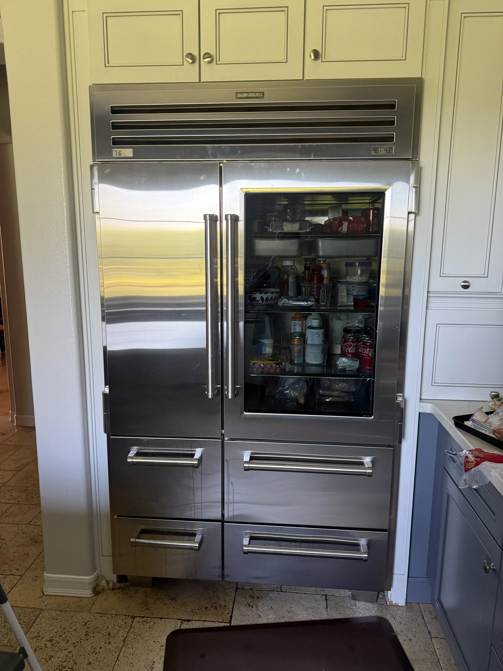A built-in Sub-Zero refrigerator in a white kitchen on a service call