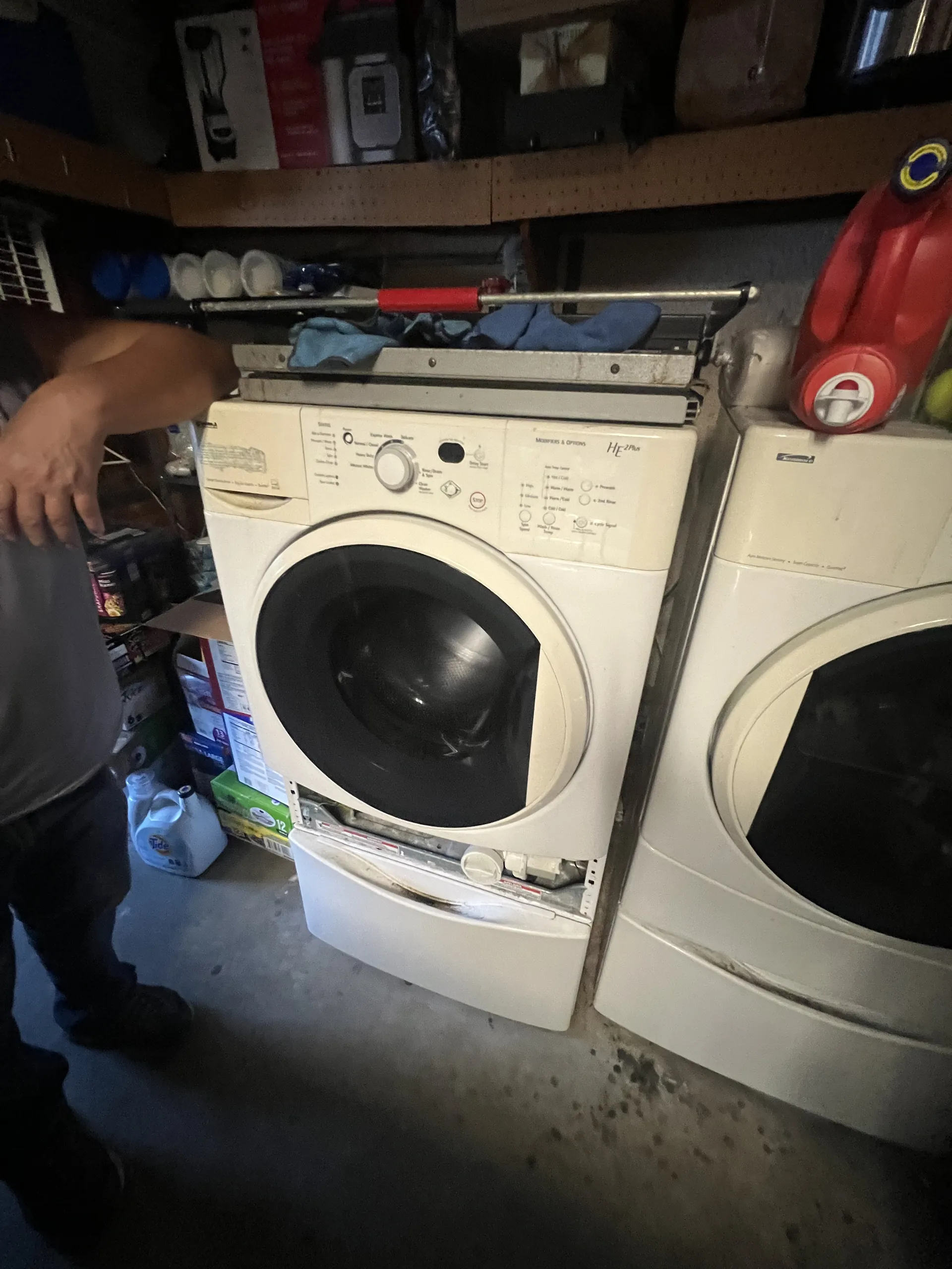 A technician working inside a front-load washer in a Valley laundry room